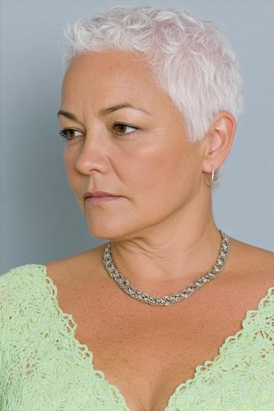 Een oudere dame met kort, wit, golvend haar en een stijlvolle, frisse uitstraling.