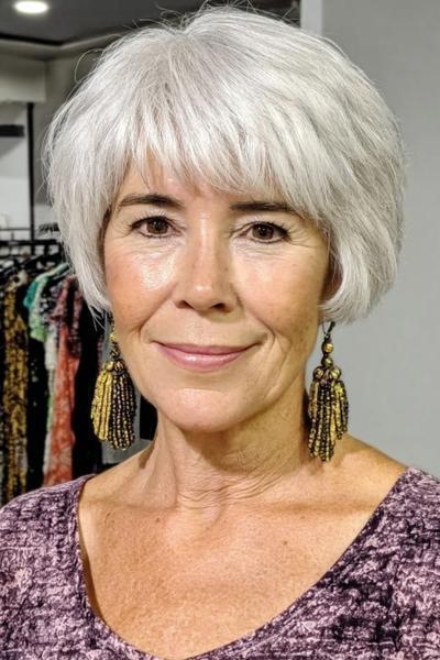 Een vrouw met kort, vlot, zilvergrijs haar in een boblijn met lichte pony.
