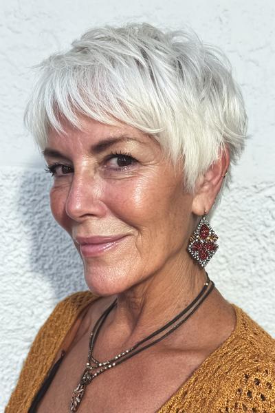 Een vrouw met een kort, vlot, witgrijs kapsel met speelse laagjes en pony.
