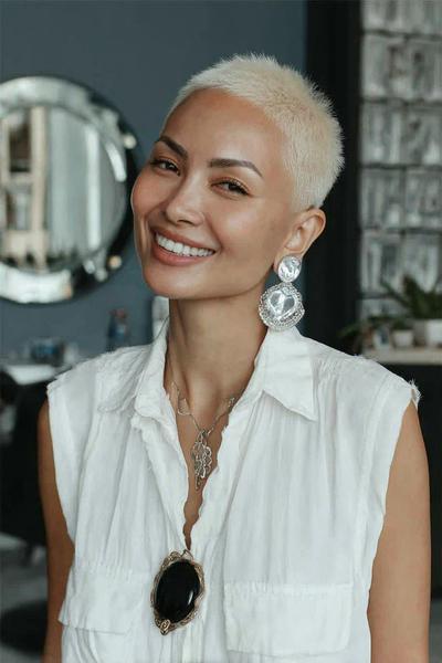 Een vrouw met een vlot, kort blond kapsel met een zeer korte, bijna geschoren coupe.