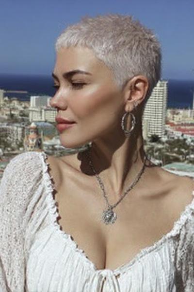 Een vrouw met een zeer kort, platinum blond kapsel in een moderne pixie stijl.