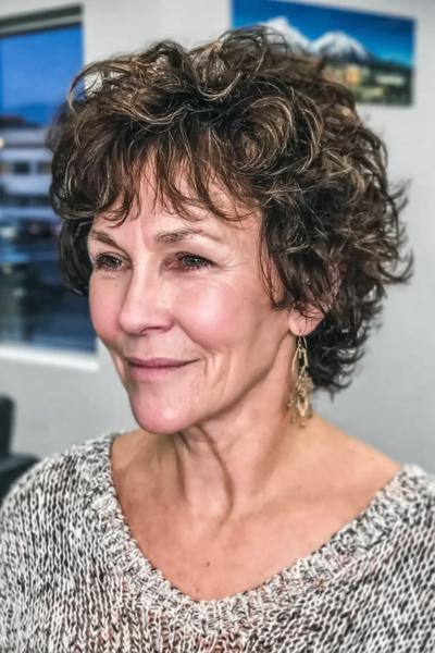 Vrouw met kort, volumineus en krullend kapsel, geschikt voor dames van 60 jaar en ouder.