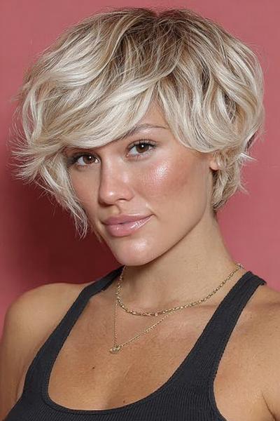Een vrouw met een kort, golvend blond kapsel met zijscheiding en volume bovenop.