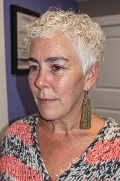 Een vrouw met kort, wit krullend haar in een vlot en modern kapsel voor 60-plussers.