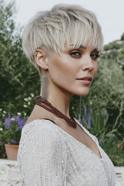 Een vrouw met een trendy kort kapsel met laagjes en een pony, in een blonde kleur.