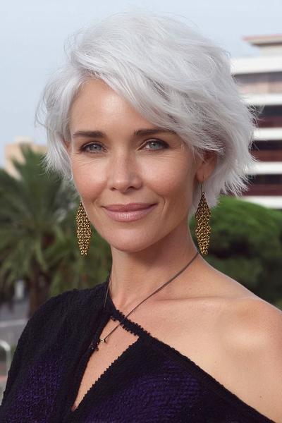 Een elegante oudere dame met een kort, golvend wit kapsel dat speels en stijlvol valt rondom het gezicht.